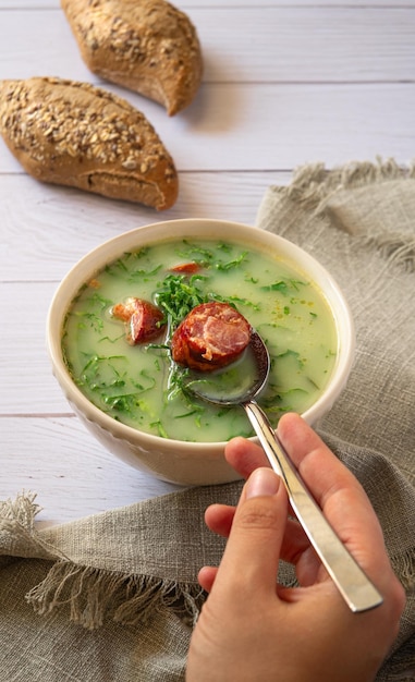 A hand holding a spoon of Portuguese Cabbage soup