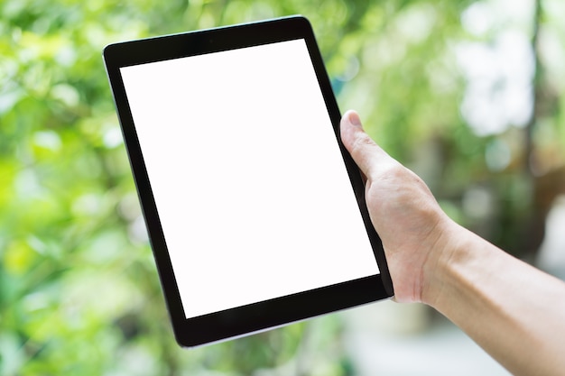 Hand holding a tablet with blank screen on green blur background