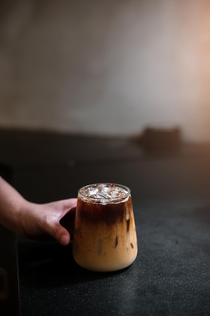 hand holding a take-out iced coffee on black table