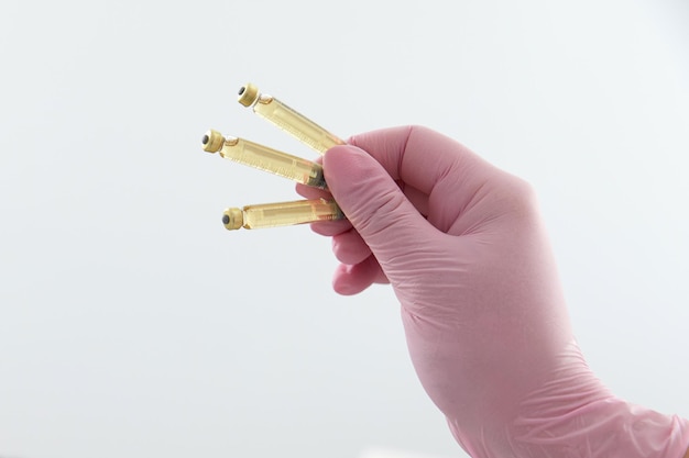 Hand holding three ampoules with liquid