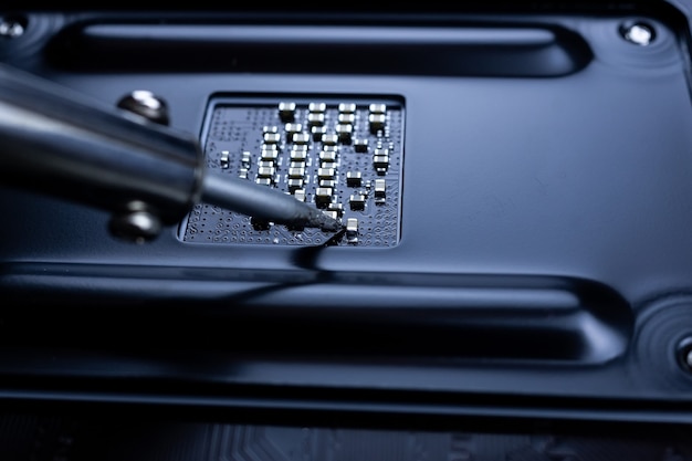 The hand holding the tin, a soldering iron solder the chip in place