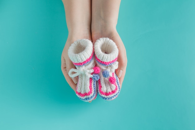 Hand holding tiny knitted booties