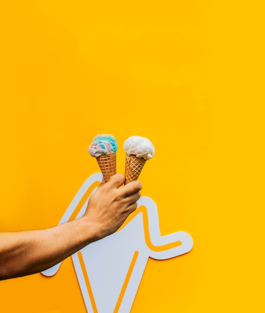 Hand holding two waffle cone ice cream isolated Hand holding two ice cream cone on yellow background Waffle cone ice cream concept on yellow background