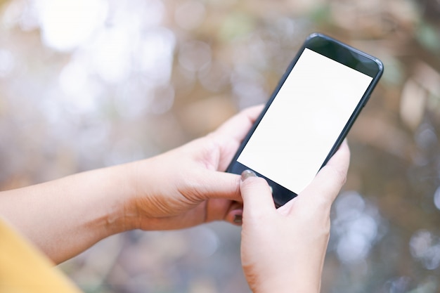 Hand holding and using a mobile phone with white blank screen