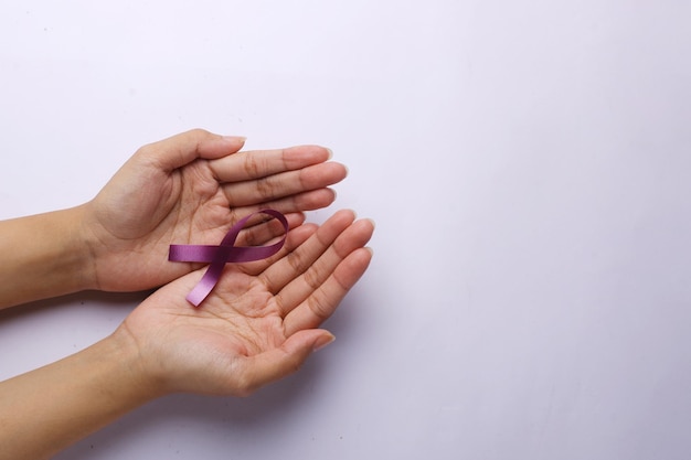 Hand holding violet ribbon World Cancer Day concept