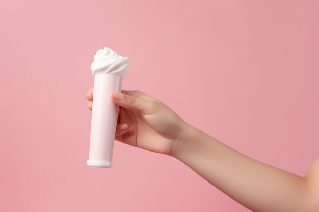 Hand holding a white cream tube isolated on clean pastel pink background Generative AI