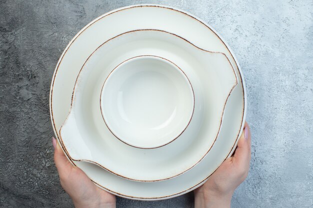 Hand holding white dinnerware set on half dark light gray surface with distressed surface