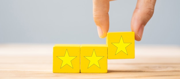 Hand holding wooden blocks with the star symbol. Customer reviews, feedback, rating, ranking and service concept.