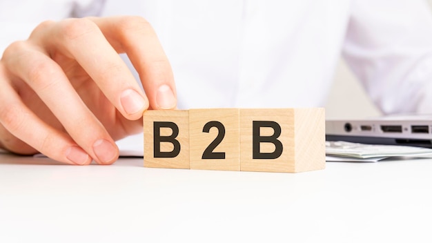 Hand holding wooden cube with B2B text on table background financial marketing and business concepts