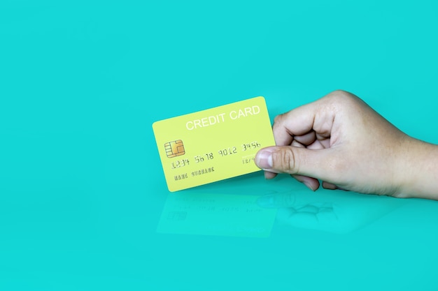 Hand holding a yellow credit card on a blue background, credit card can be used to pay for goods or services, credit card concept, holding credit card clipping path.