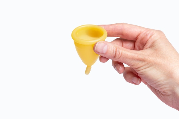 Hand holding a yellow menstrual cup on a white background Women's health concept Eco friendly concept Zero waste concept