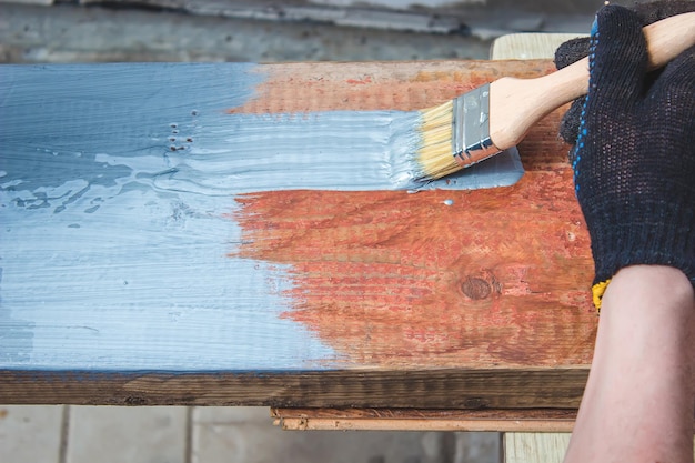 Hand holds a brush apply varnish paint on the board board painting