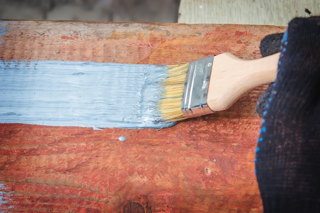 Hand holds a brush apply varnish paint on the board board painting