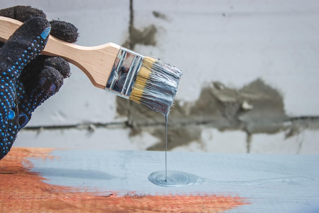 Hand holds a brush apply varnish paint on the board board painting