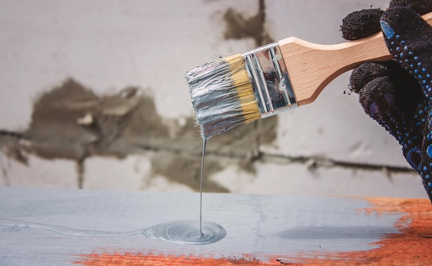 Hand holds a brush apply varnish paint on the board board painting