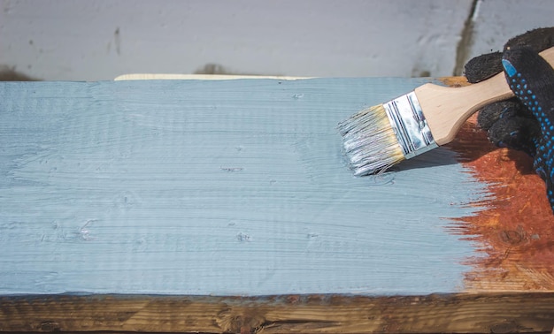 Hand holds a brush apply varnish paint on the board board painting