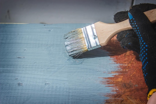 Hand holds a brush apply varnish paint on the board board painting