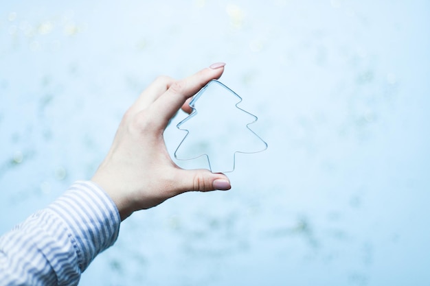 Photo a hand holds a christmas tree shaped cookie cutter bake christmas cookies