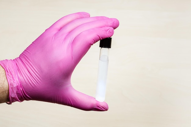 Hand holds closed test tube over light table