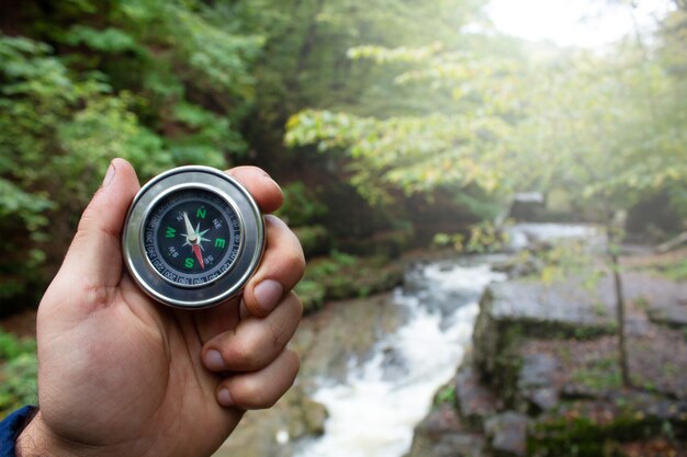 Hand holds a compass on the background of the river