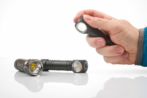 Hand holds a flashlight against the background of other flashlights on a white background camping and household item