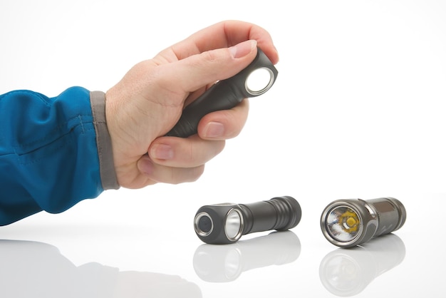 Hand holds a flashlight against the background of other flashlights on a white background camping and household item