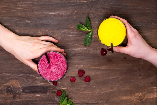 Photo the hand holds a glass of orange and currant juice for drinking on the old wooden table