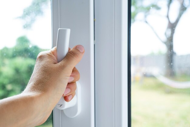 Photo the hand holds the handle of a plastic doubleglazed window closing and opening the window with a rotary mechanism the position of the handle for ventilation microventilation