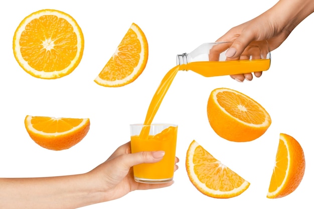 The hand holds a horse with orange juice The hand holds a bottle of juice and pours into a glass Flying pieces of orange Isolated on white background