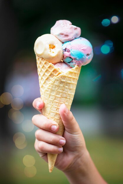 Hand holds ice cream cone on colorful background