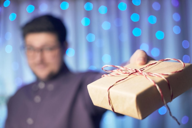 Hand holds a new year gift on the background of a garland