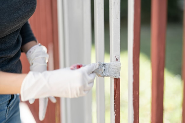 Hand holds a paintbrush and paints the fence Repair