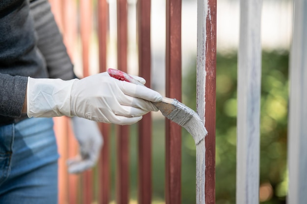 Hand holds a paintbrush and paints the fence Repair