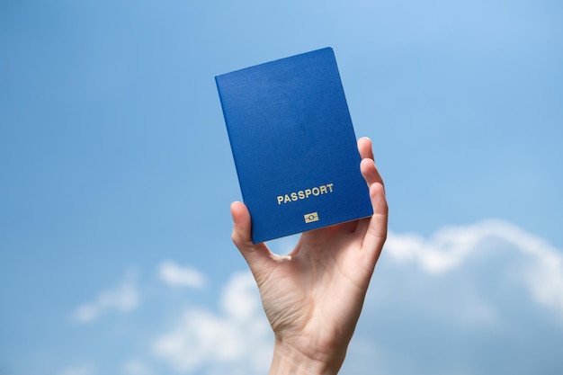 Hand holds passport on background of blue sky with clouds Travel concept