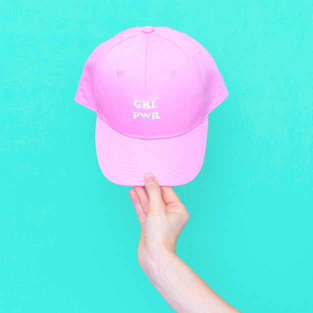 Hand holds pink fashion cap. Girl power aesthetic minimal vibes.