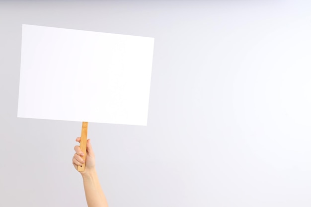 Hand holds protest sign on light background