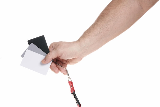 Hand holds a set of gray cards for adjusting white balance on a white background