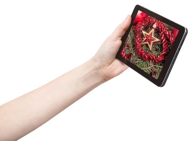 Hand holds tablet pc with red star and tinsel