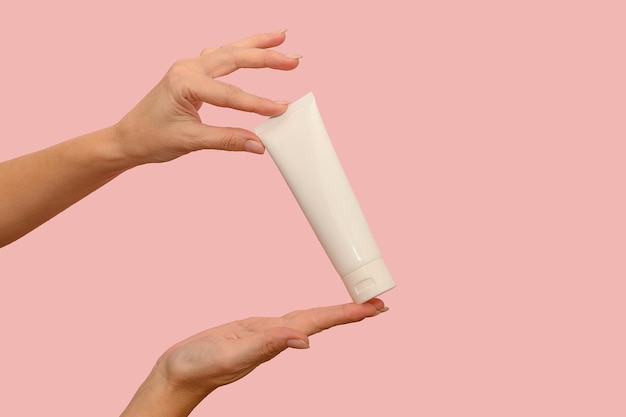 Hand holds a white container with cosmetic cream For body care