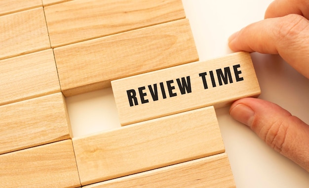 Hand holds a wooden cube with the text REVIEW TIME