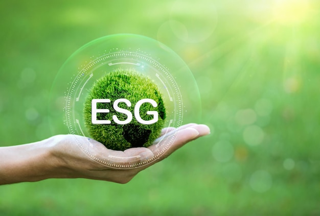 Hand of human holding green earth ESG icon with sunlight on a green background. for Environment Soci