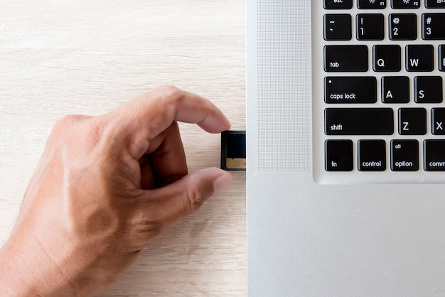 Hand inserting memory card into laptop slot