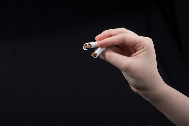 Hand is breaking a cigarette on black background