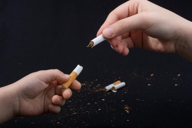 Hand is breaking a cigarette on black background