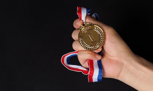 Hand is hold gold medal on black background