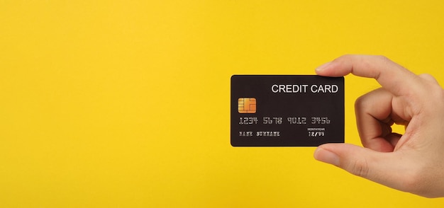 Hand is holding black credit card on yellow backgroundx9