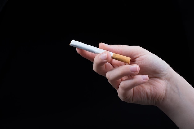 Hand is holding cigarette on black background