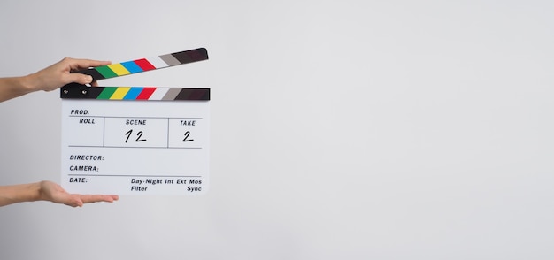 A hand is holding clapper board or movie slate use in video production and movie, film, cinema industry on black background. It has written in number.