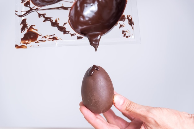 a hand is holding an egg with chocolate sauce on it