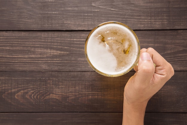 Hand is holding a glass of beer in the pub